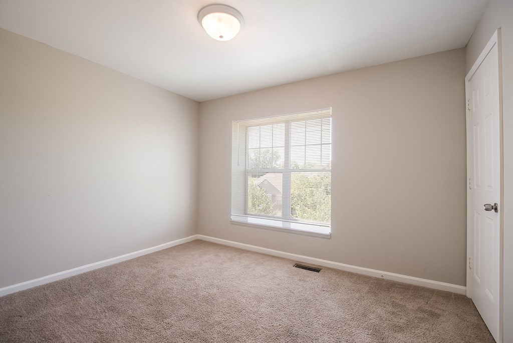 A room with a window and carpeted floor.