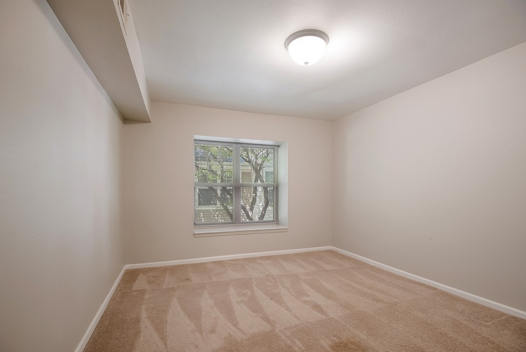 A room with a carpeted floor and a window.