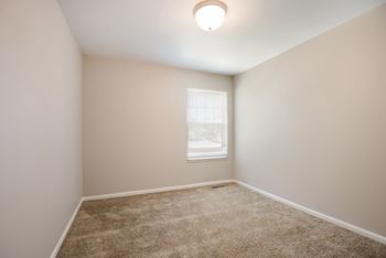A room with a carpeted floor and a window.