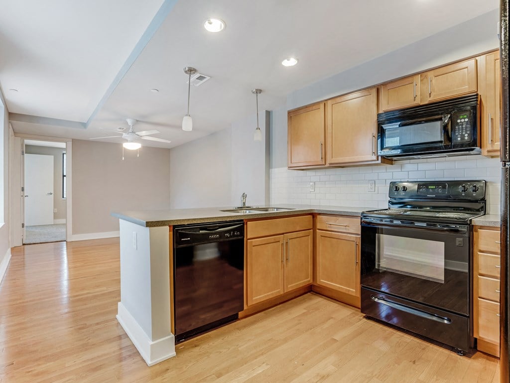 an empty kitchen with wooden cabinets and a stove and a microwave