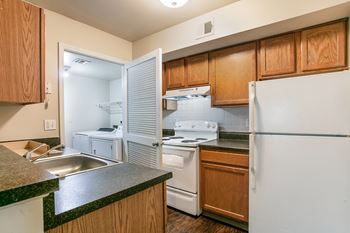 A kitchen with a white refrigerator, white stove, and wooden cabinets.