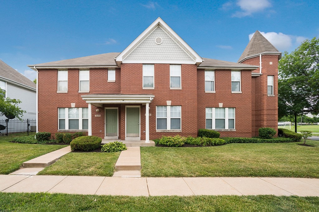 a brick house with a sidewalk in front of it