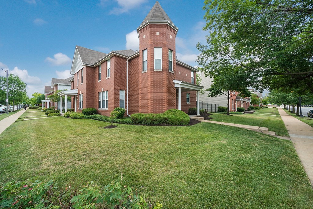 a large brick building with a tower on the side of a sidewalk
