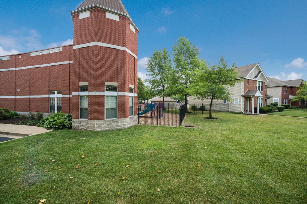 a brick building with a fence in front of a yard
