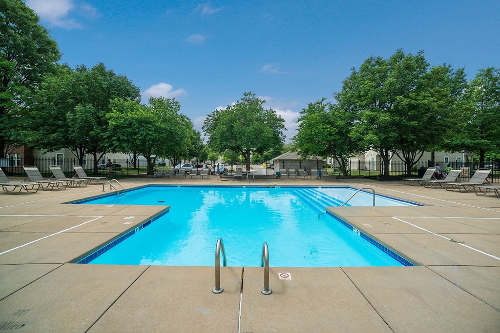 a swimming pool with trees and chairs around it