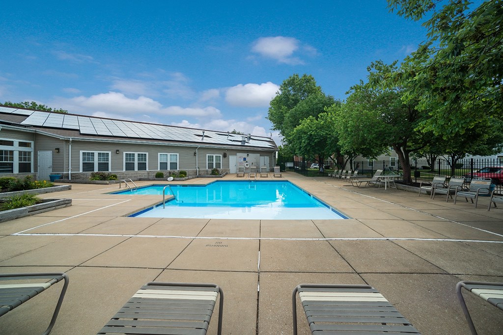 a swimming pool with trees and a building in the background