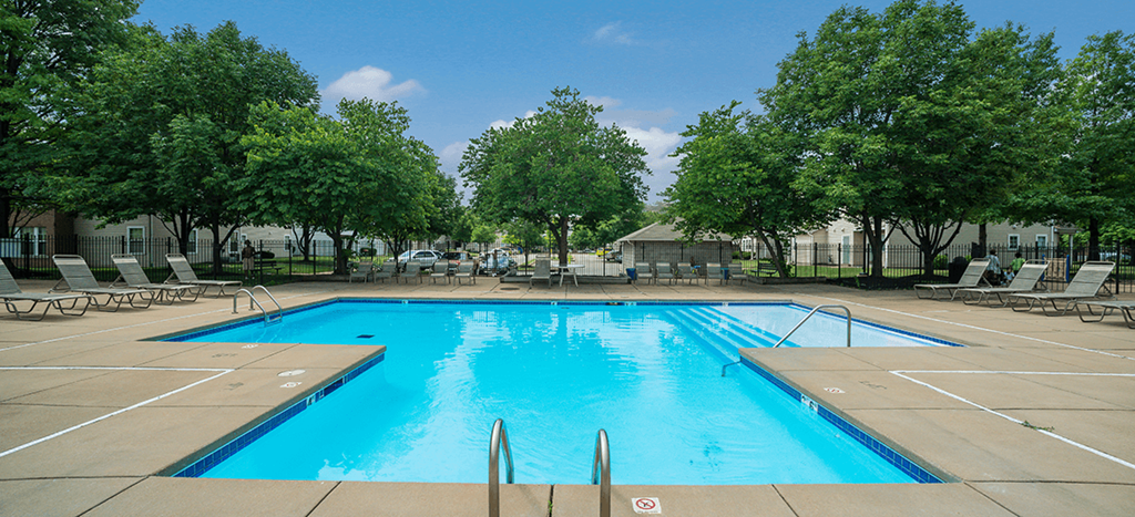 a swimming pool with trees and chairs around it