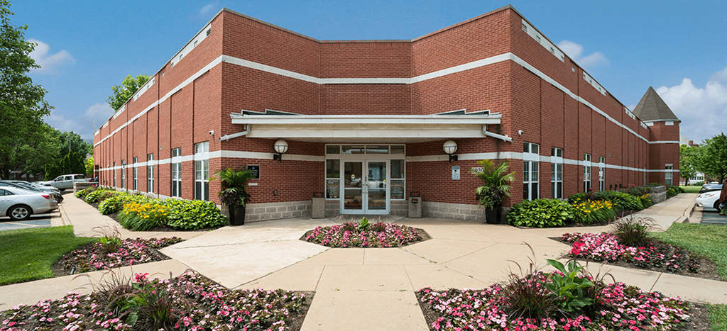 the front of Murphy Park Apartments leasing office a brick building with a sidewalk and flowers