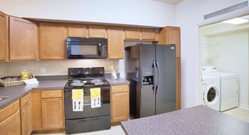 A kitchen with a black stove top oven and a black microwave above it.