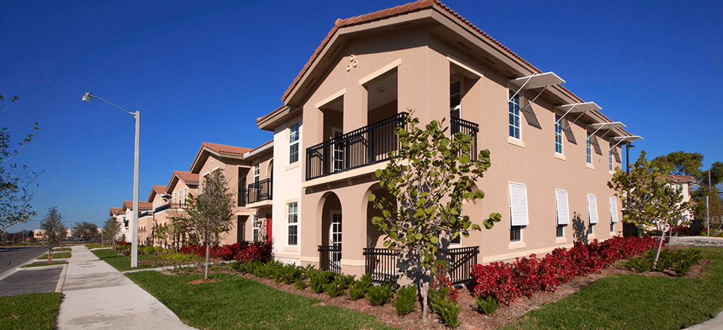 a row of apartments with balconies and trees and a sidewalk