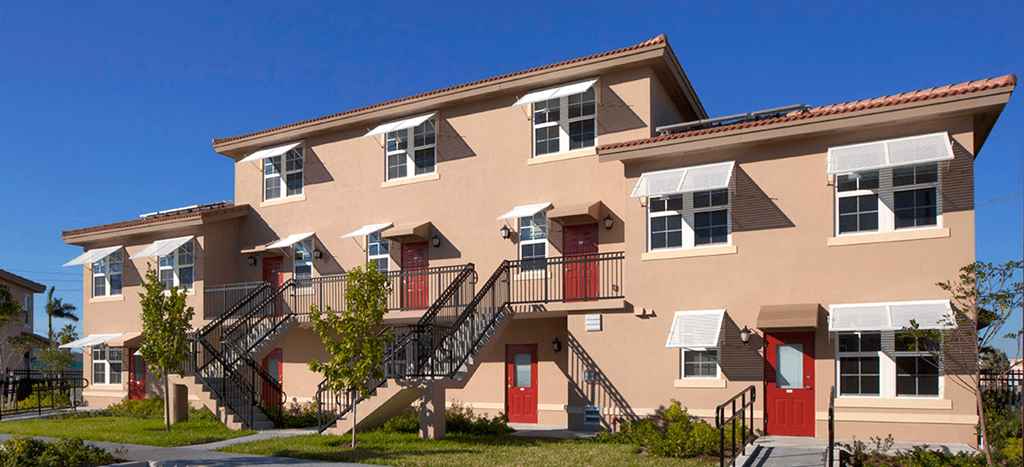 a row of apartments with stairs and red doors at Northpark at Scott Carver Apartments