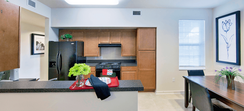 a kitchen with wooden cabinets and a black counter top at Northpark at Scott Carver Apartments