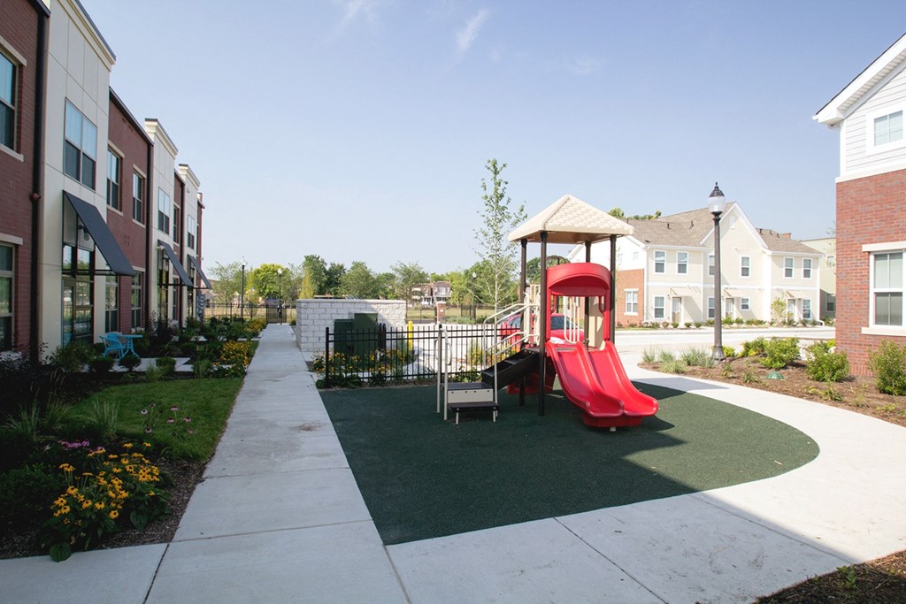 a playground in the middle of an apartment complex with a red slide