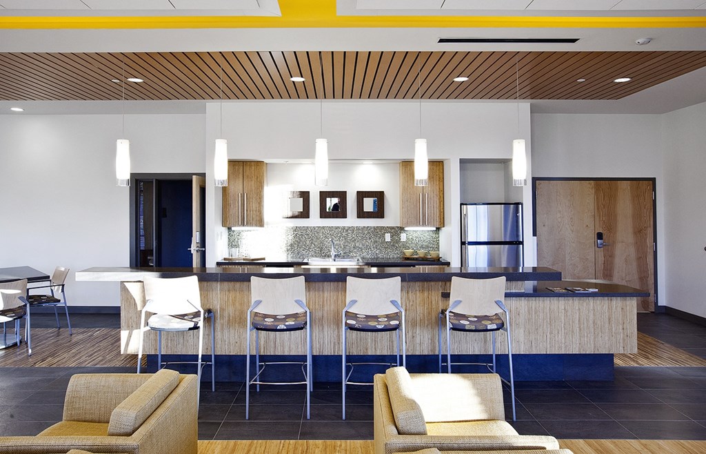 a kitchen with a bar and chairs in a hotel room