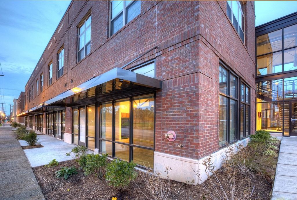 a brick building with large windows and a sidewalk