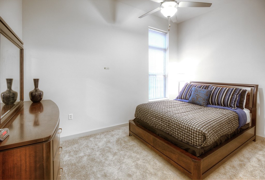 a bedroom with a bed and a dresser and a window