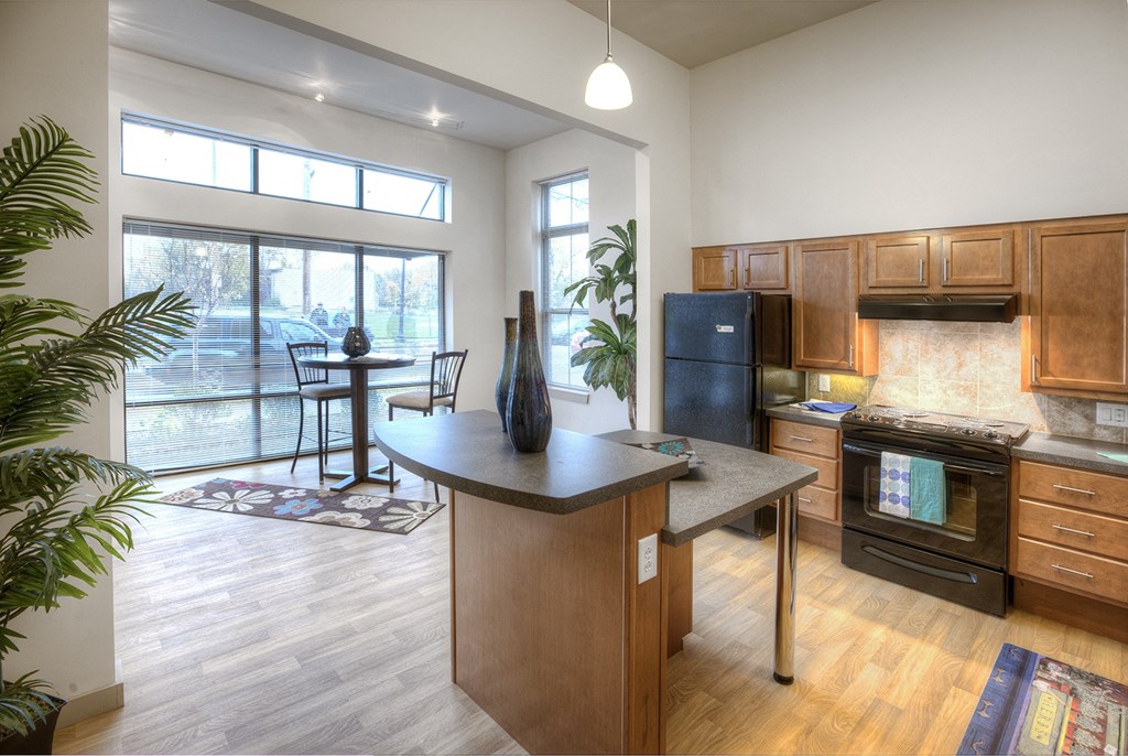an open kitchen and living room with a view of a balcony and a kitchen island
