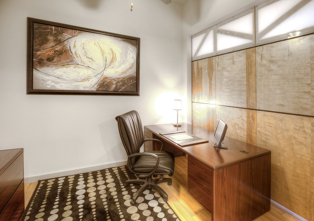 a home office with a desk and a painting on the wall