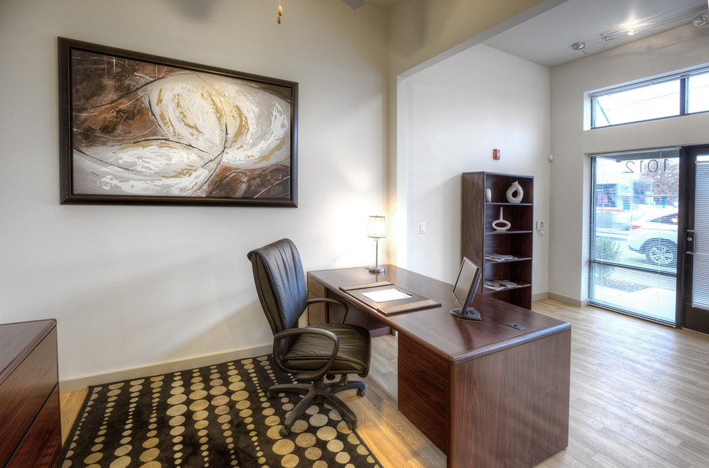 an office with a desk and a painting on the wall