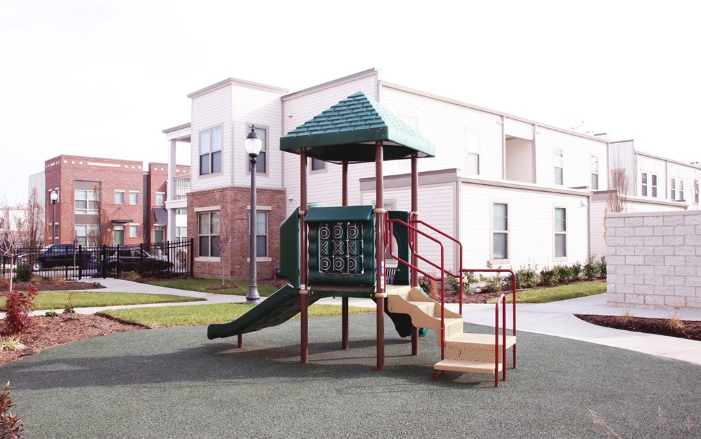 a playground with a slide in front of some apartments