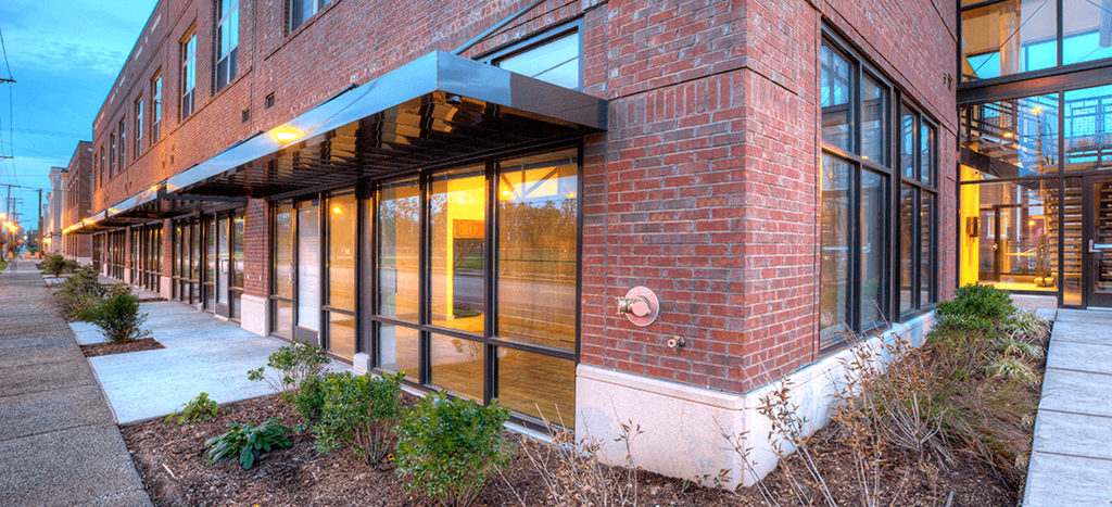 a large brick apartment building with large windows and a sidewalk