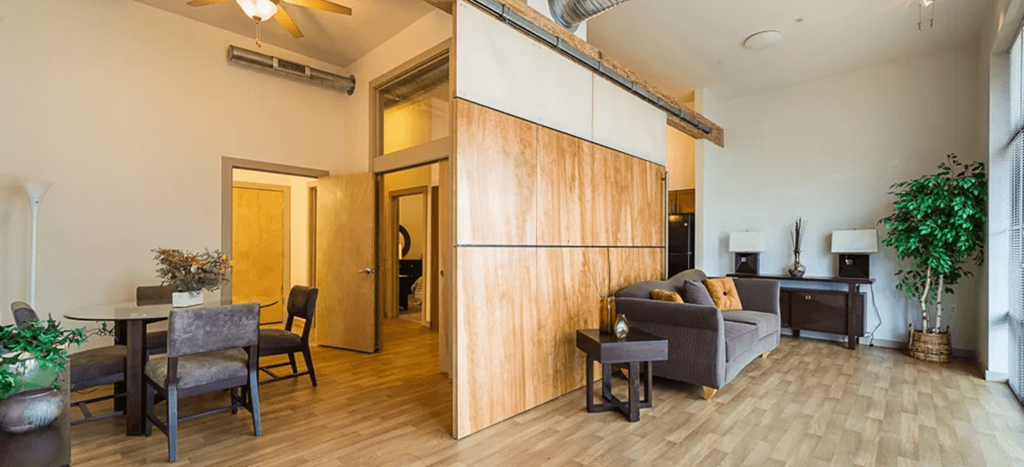 North Sarah Apartments model unit living area and dining room with wood panels on the walls and industrial accents