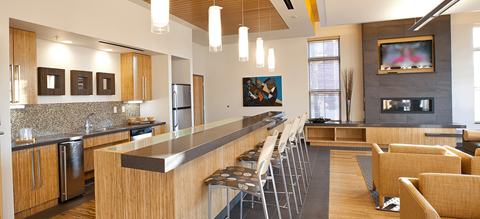 a large kitchen with a long bar with chairs and a fireplace
