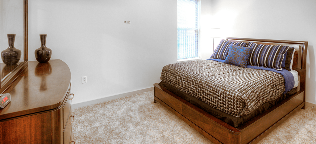 a bedroom with a bed and a dresser and a window