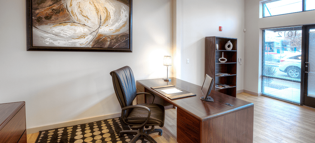 a home office with a desk and a painting on the wall