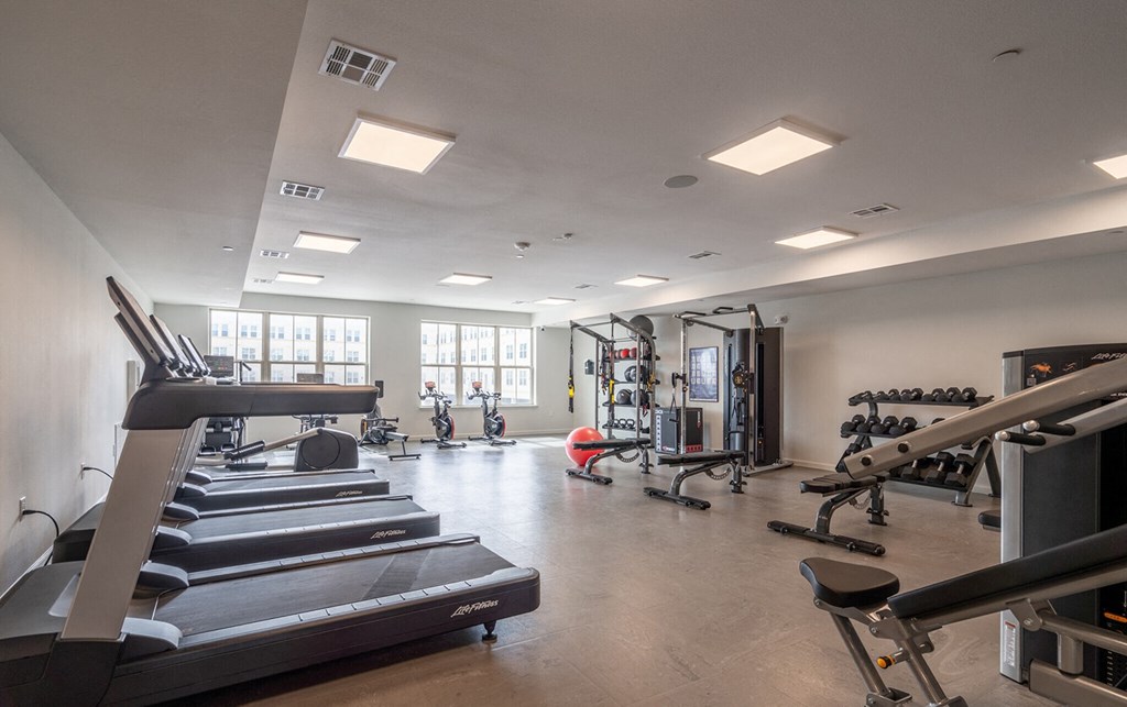 a gym with treadmills and other exercise equipment and windows