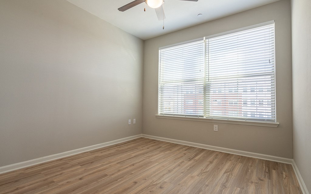 an empty room with wood floors and a large window