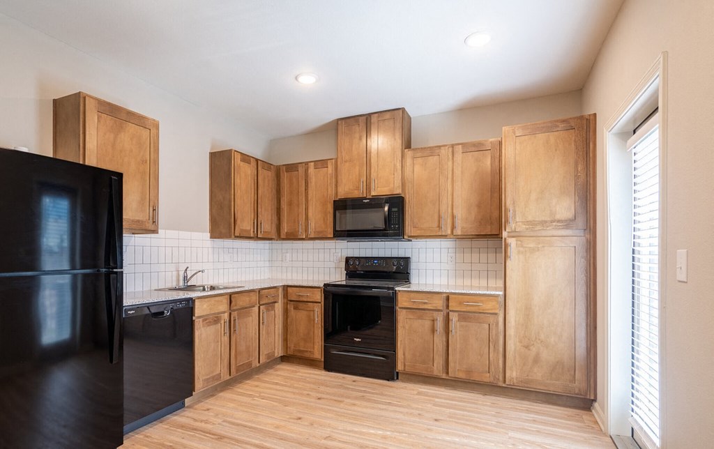 an empty kitchen with wooden cabinets and black appliances