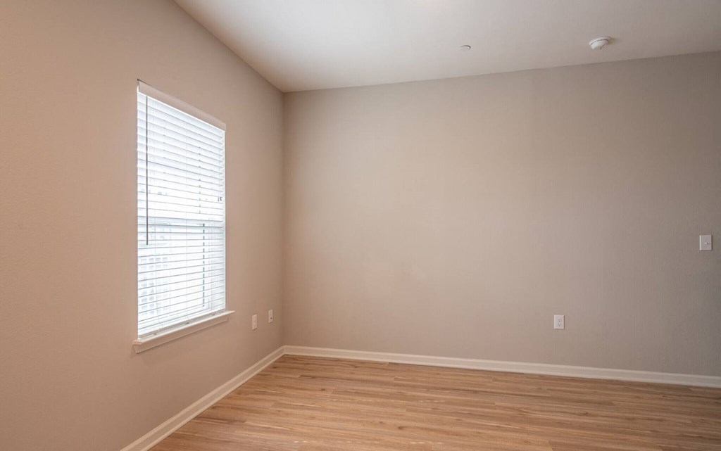 an empty room with a window and wooden floors