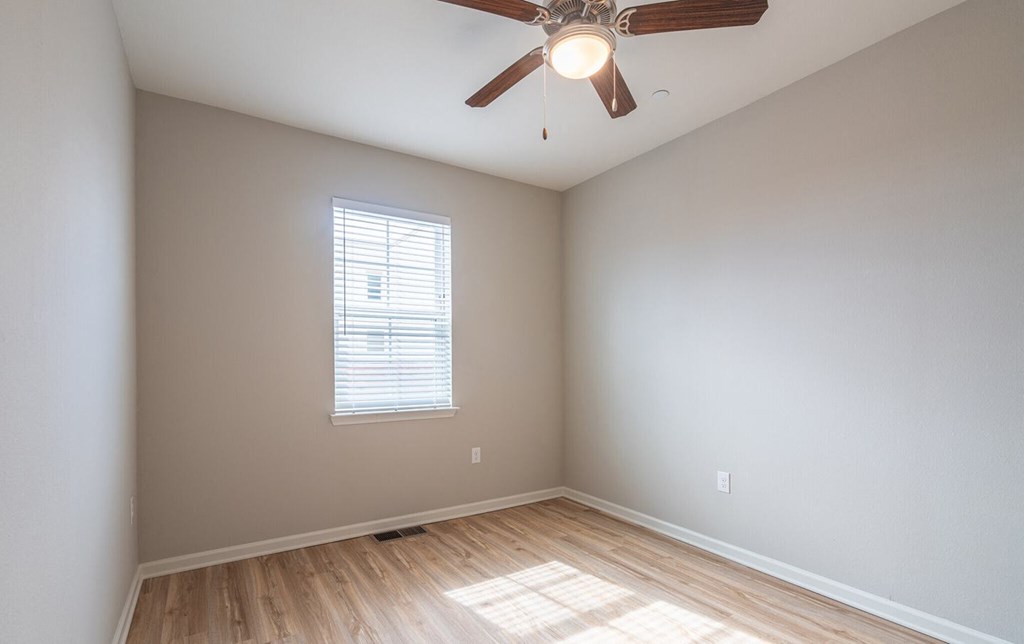 an empty room with a ceiling fan and a window