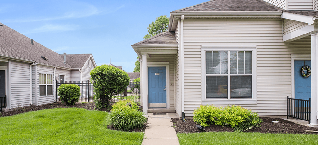 a white apartment home with a blue door on a grass yard at Parsons Place Apartments