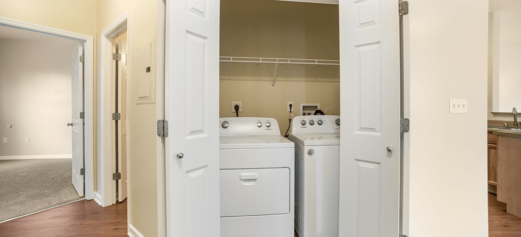 an empty kitchen with white appliances and a door to the laundry room at Parsons Place Apartments