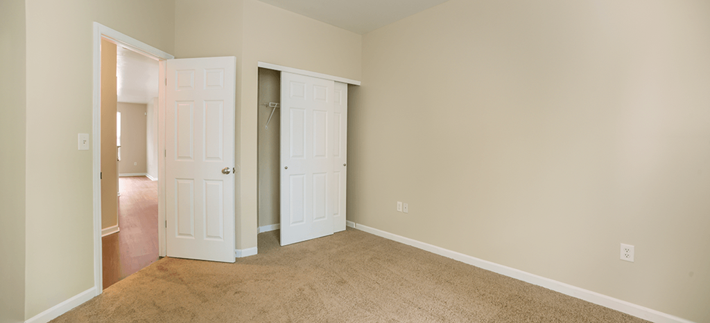 an empty bedroom with two doors and a carpeted floor