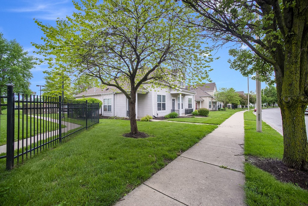 a sidewalk in front of white houses with a black fence