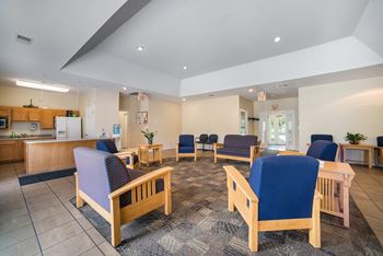 a lobby with chairs and tables and a kitchen