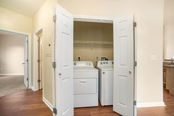 an empty kitchen with white appliances and a laundry room with white doors