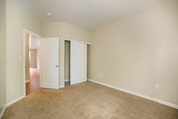 an empty bedroom with two doors and a carpeted floor
