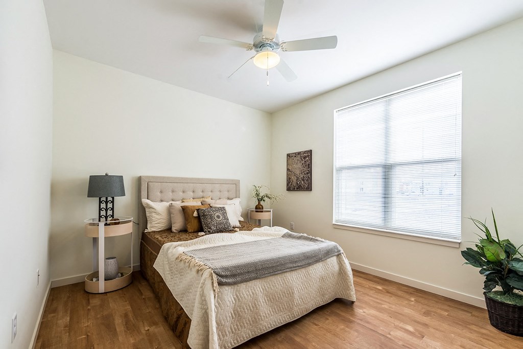 a bedroom with a bed and a ceiling fan at Legacy Pointe at Poindexter Apartments & Townhomes