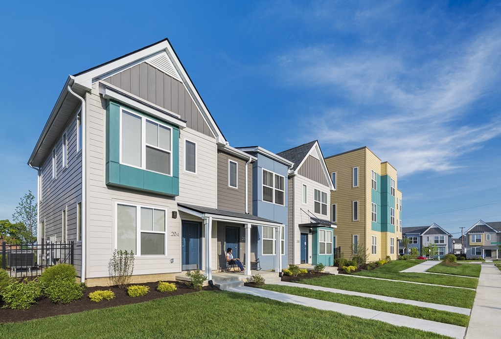 the exterior of townhomes with green grass in the front yard at Legacy Pointe at Poindexter Apartments & Townhomes