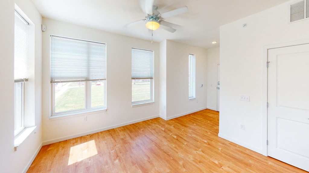 an empty room with wood floors and windows and a ceiling fan at Legacy Pointe at Poindexter Apartments & Townhomes