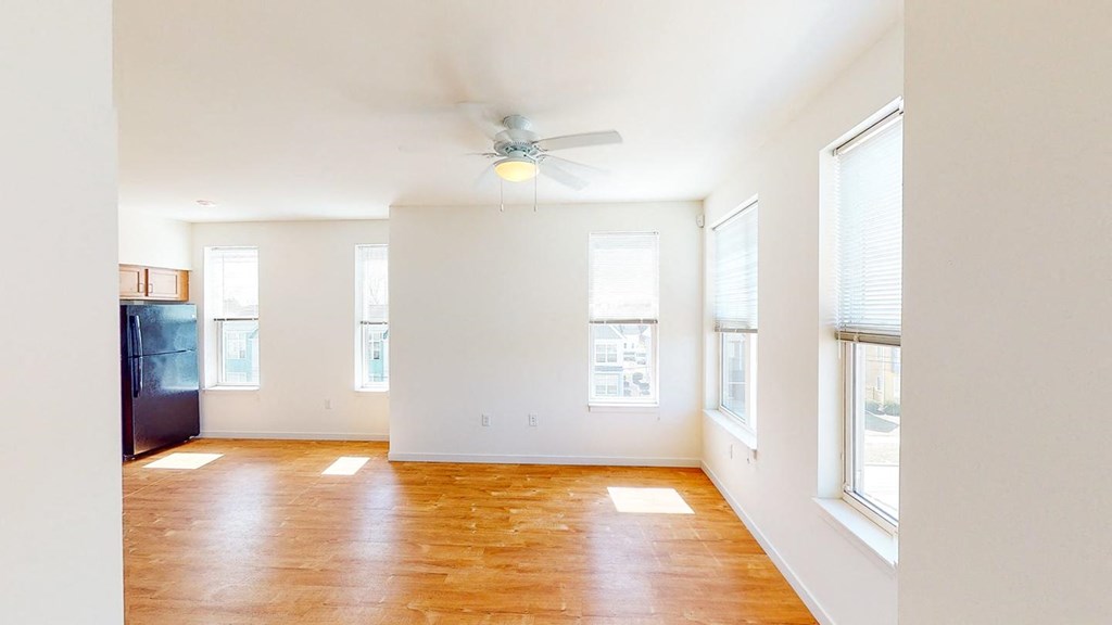 an empty living room with a ceiling fan and windows at Legacy Pointe at Poindexter Apartments & Townhomes