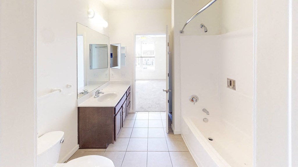 a bathroom with a shower sink and a toilet at Legacy Pointe at Poindexter Apartments & Townhomes