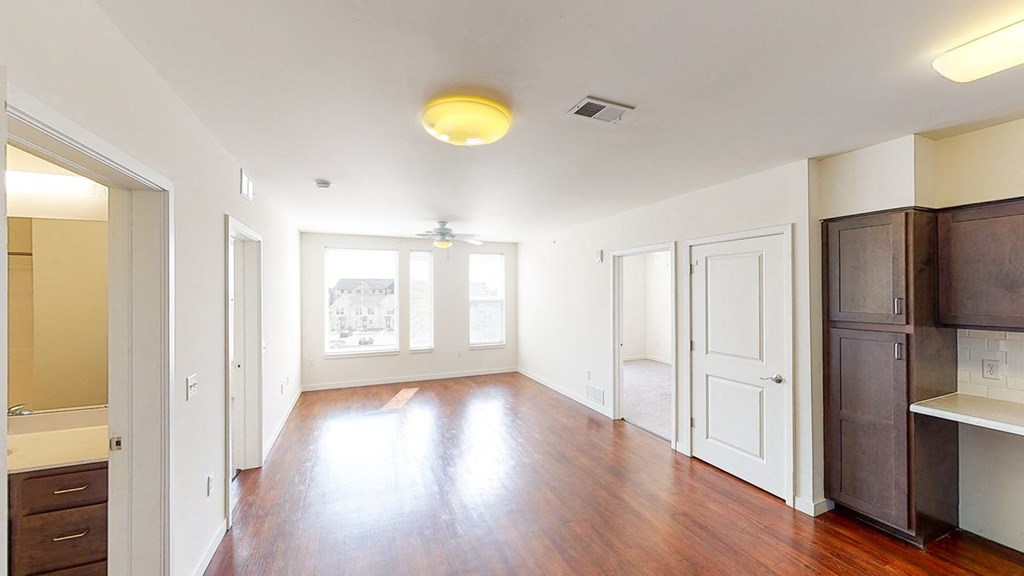 an empty living room with wood floors and white walls at Legacy Pointe at Poindexter Apartments & Townhomes