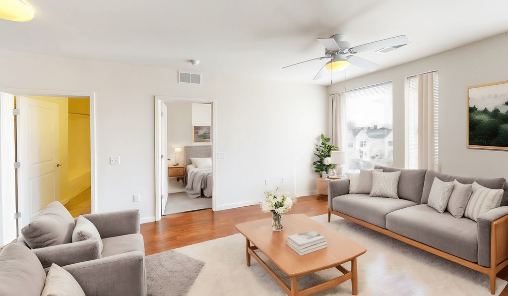 a living room with a couch and a coffee table and a ceiling fan at Legacy Pointe at Poindexter Apartments & Townhomes