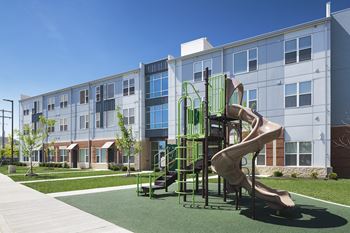 A playground with a green slide in front of a building.