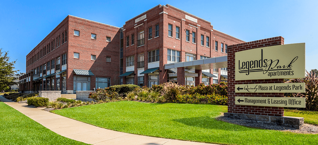 a large brick building with a sign in front of it for Quimby Plaza Apartments